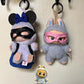 Adorable Labubu dolls in superhero costumes, one with black mask and mouse ears, the other in a bunny suit, perfect for collectors.