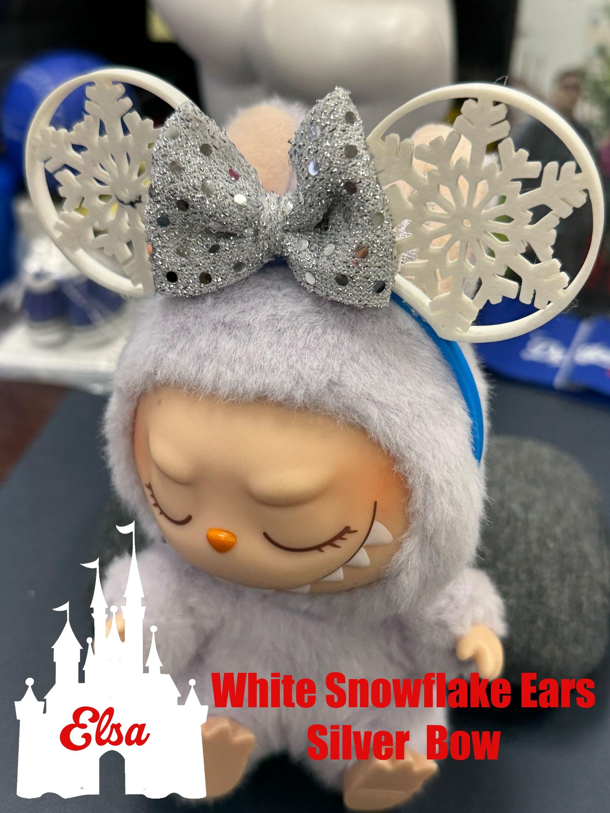 Elsa-inspired Labubu doll with white snowflake ears and a glittery silver bow, perfect for winter-themed accessories.